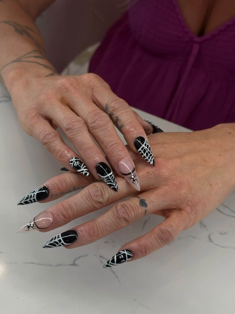 Pointed black nails with white spiderweb details at Jimmy Nails & Spa.