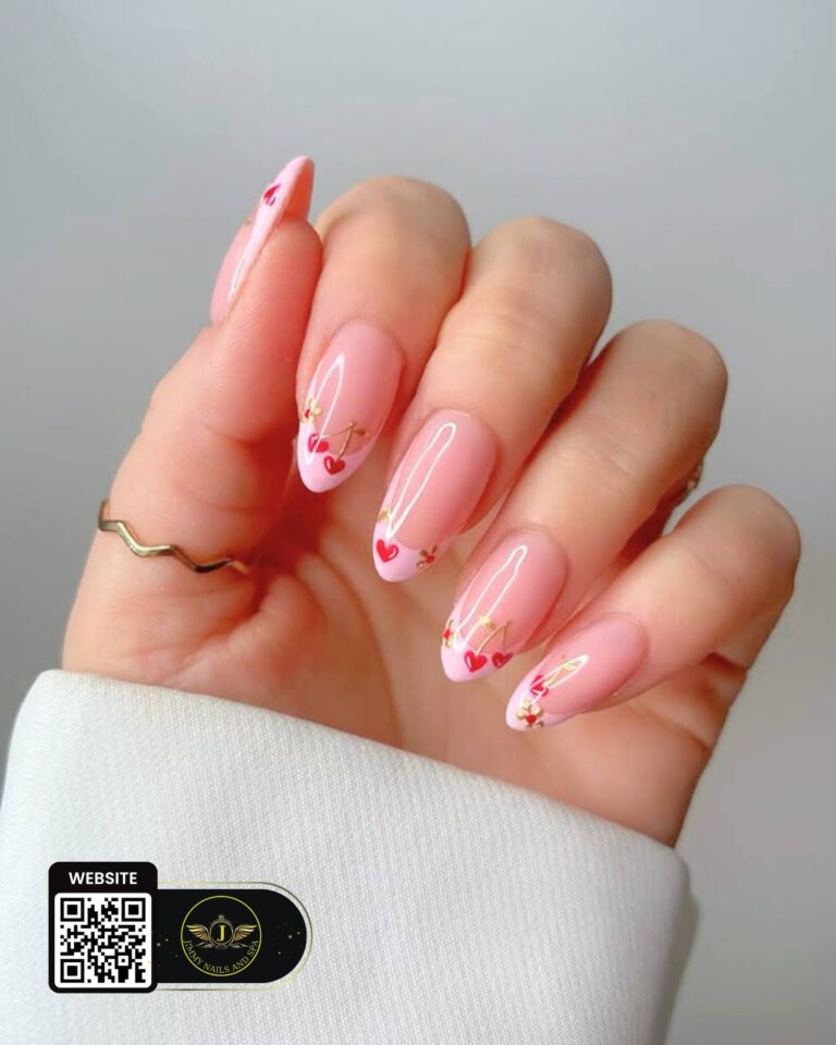 Pink almond nails with red heart accents and gold details by Jimmy Nails & Spa.